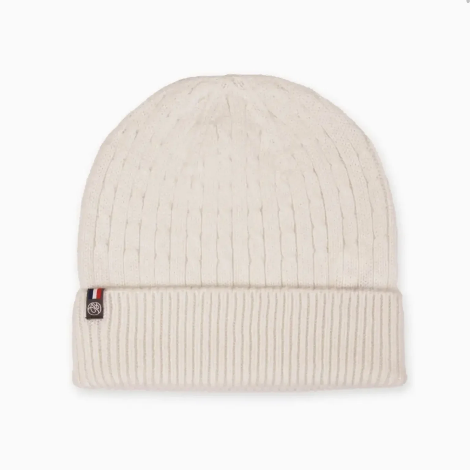 Bonnet beige en maille côtelée porté par un homme avec une écharpe dans un environnement extérieur hivernal.