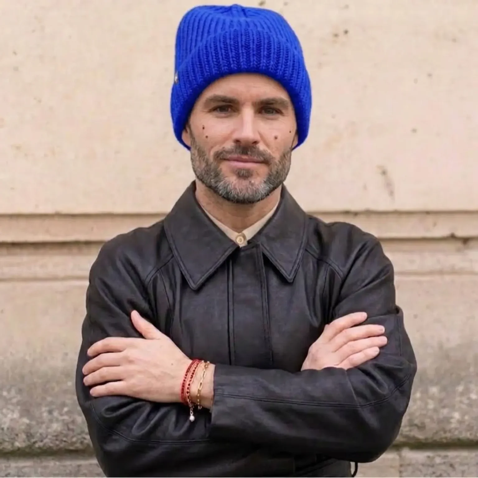 Bonnet CLAIRE, bleu en maille côtelée porté par un homme dans un environnement urbain extérieur.