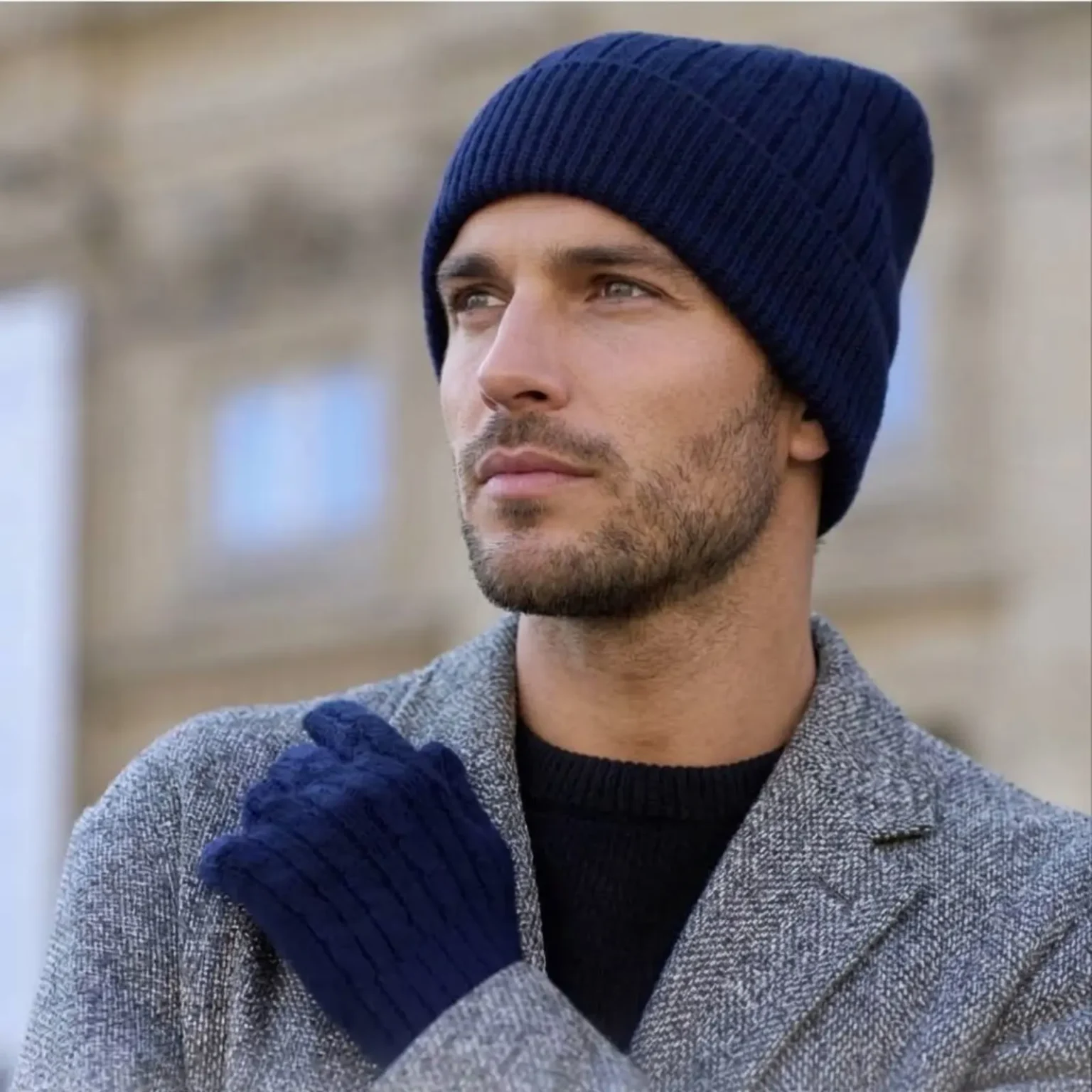 Bonnet bleu en maille côtelée porté par un homme dans un environnement urbain extérieur.