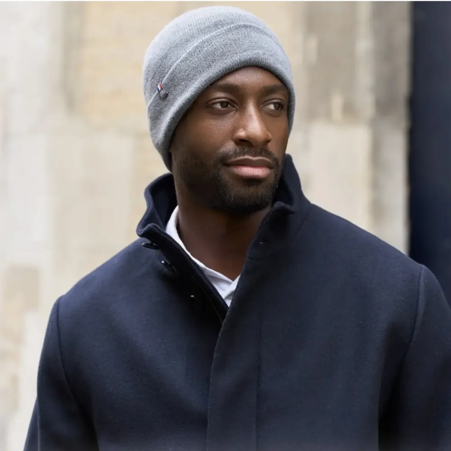 Bonnet homme gris en maille côtelée porté par un homme dans un environnement extérieur.