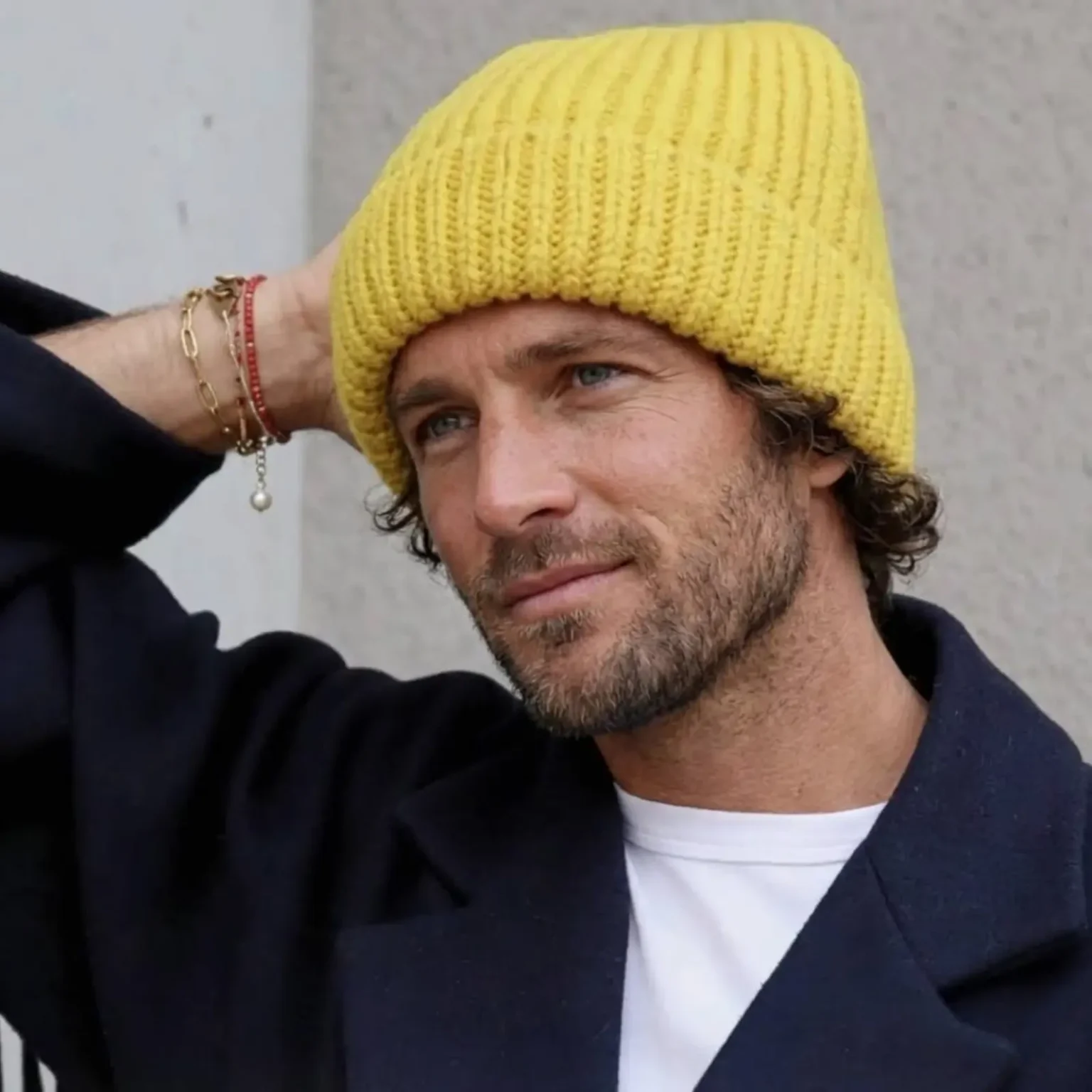 Bonnet CLAIRE, jaune en maille côtelée porté par un homme dans un environnement urbain extérieur.