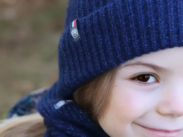 Bonnet pailleté enfant bleu policier en maille côtelée porté par un enfant dans un environnement extérieur.