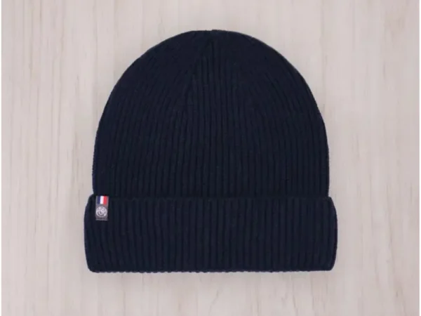 Bonnet Perrine en maille côtelée bleu policier présenté de face sur un fond en bois clair avec une étiquette tricolore PmP Premium.
