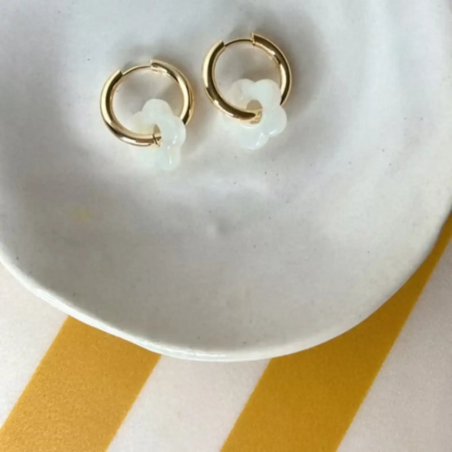 Boucles d'oreilles enfant Les Mini Flowers blanc présentées sur une coupelle blanche.