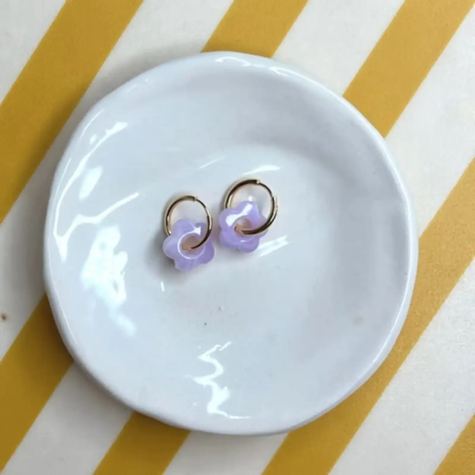 Boucles d'oreilles enfant Les Mini Flowers lavande présentées sur une coupelle blanche.