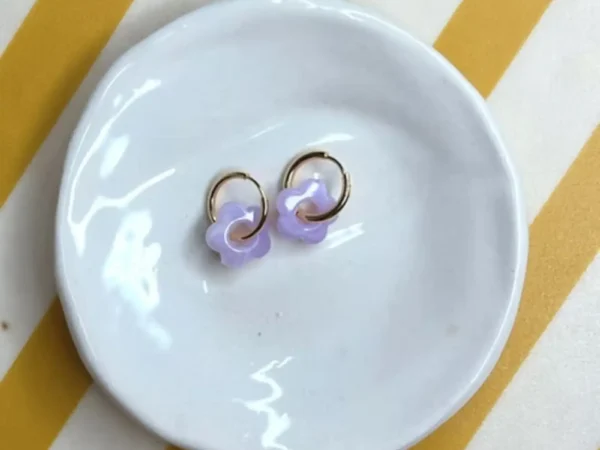 Boucles d'oreilles enfant Les Mini Flowers lavande présentées sur une coupelle blanche.