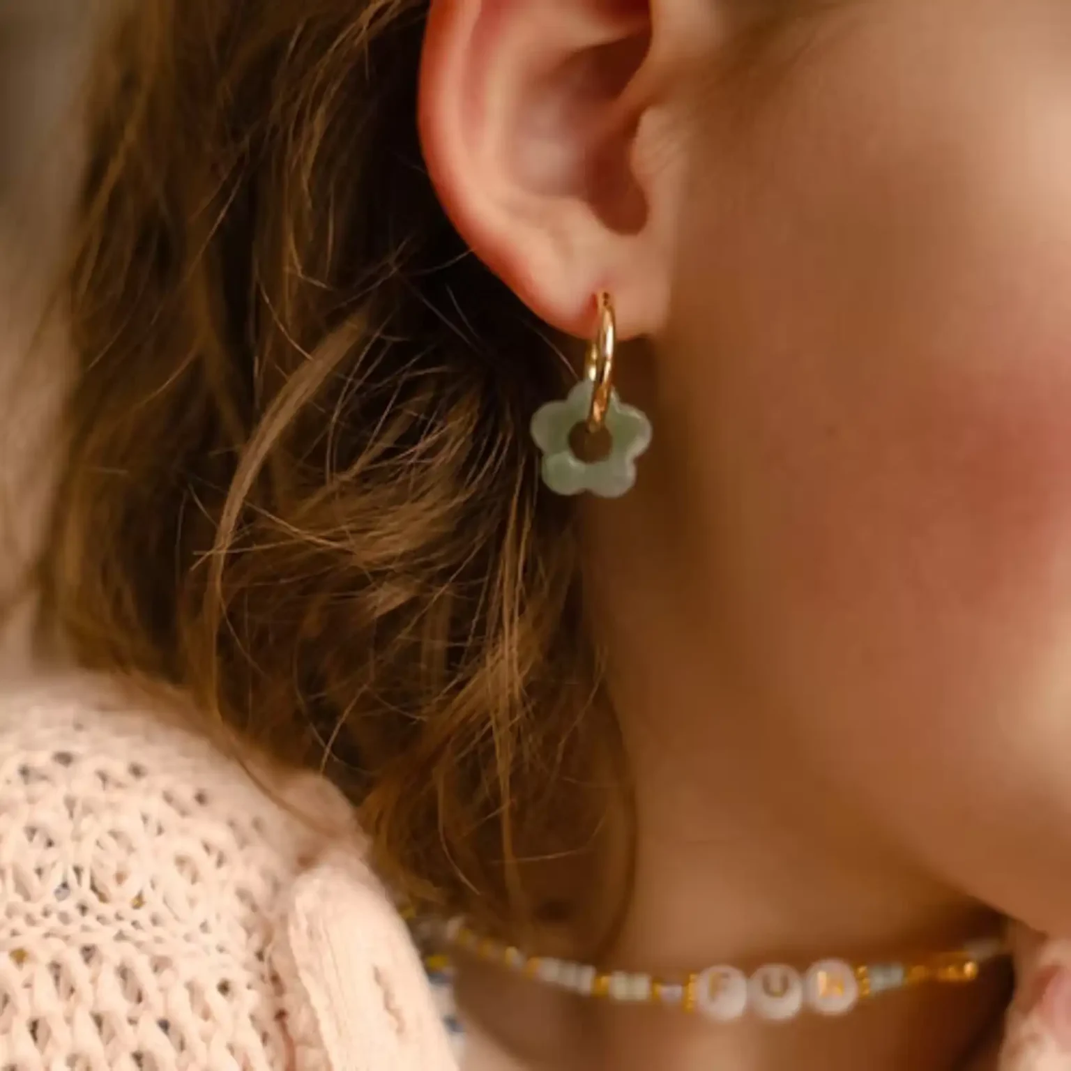 Boucles d'oreilles enfant Les Mini Flowers couleur eau portées à l'oreille.